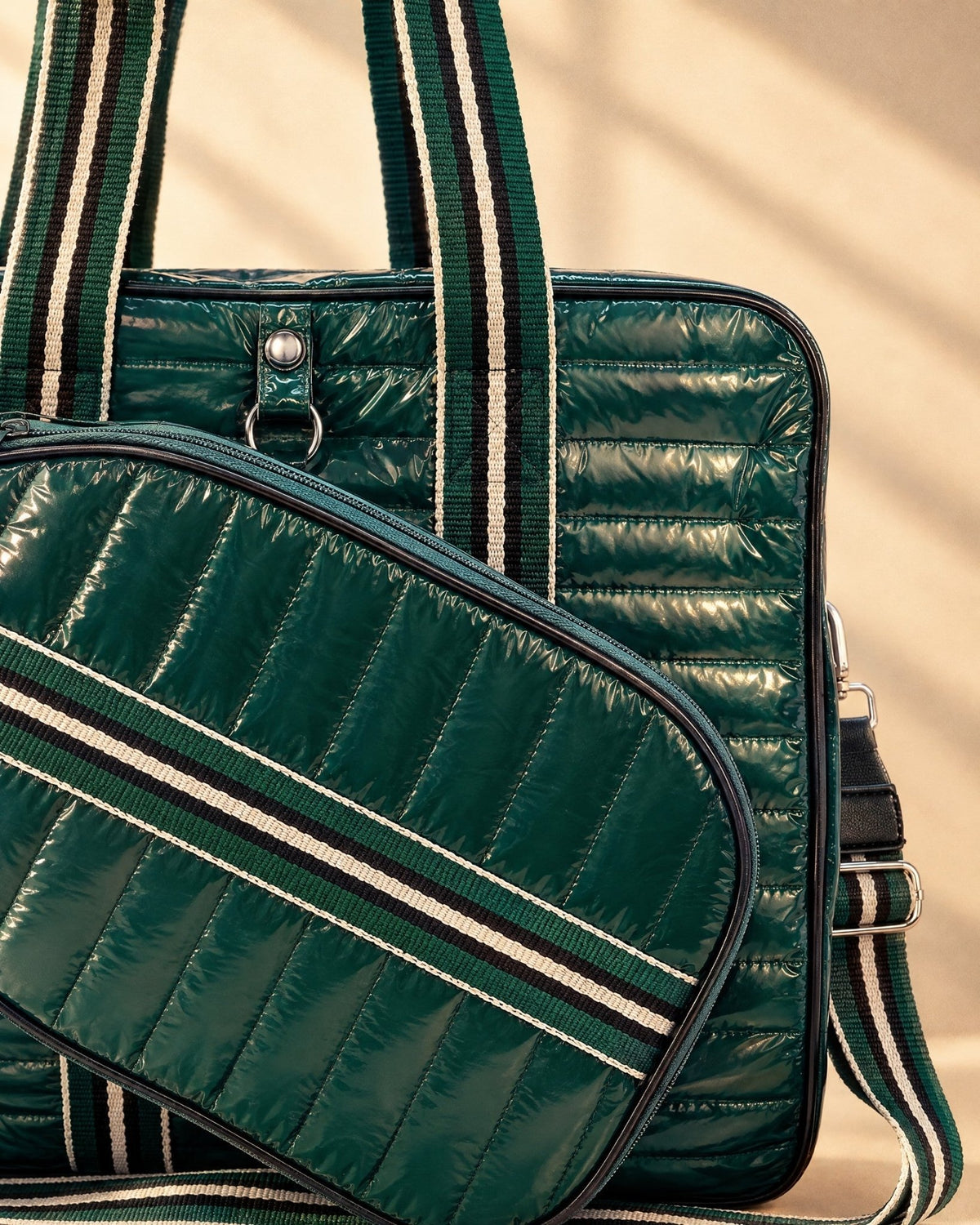 Close-up of the Roqueta's glossy dark green quilting, a striped handle and the zip of the paddle-shaped cover