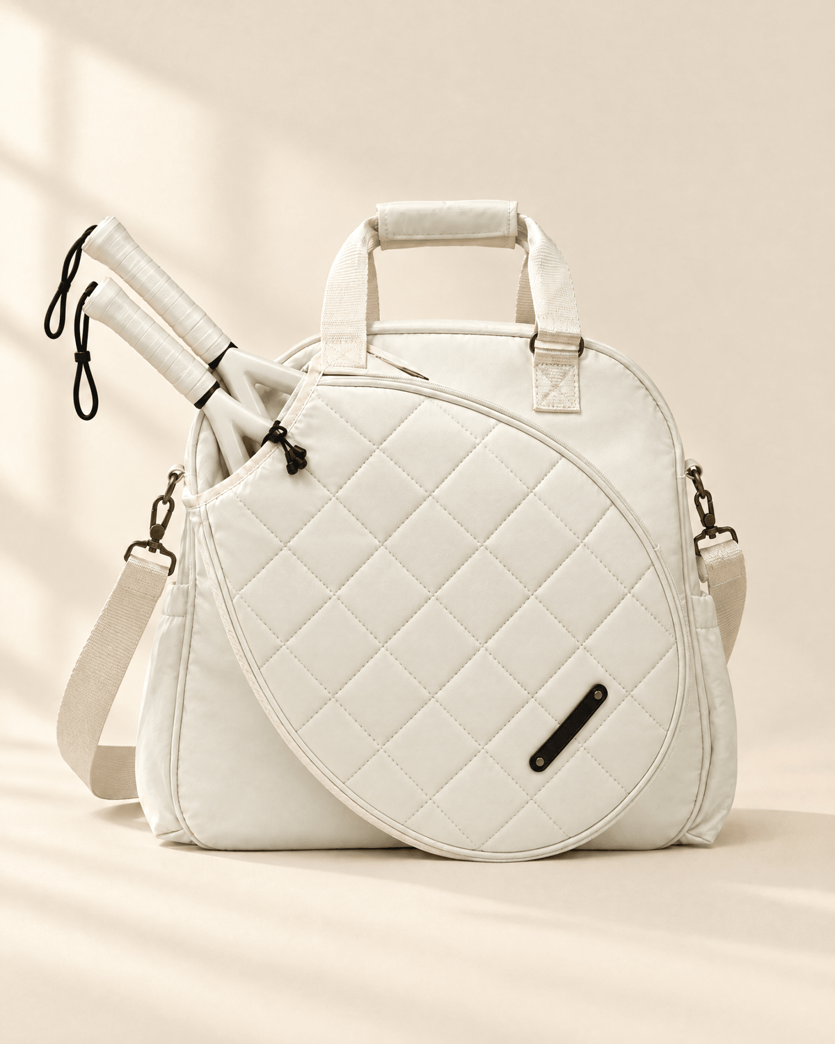 The Las Brisas Racket Bag in white, with two padel rackets in the quilted front compartment
