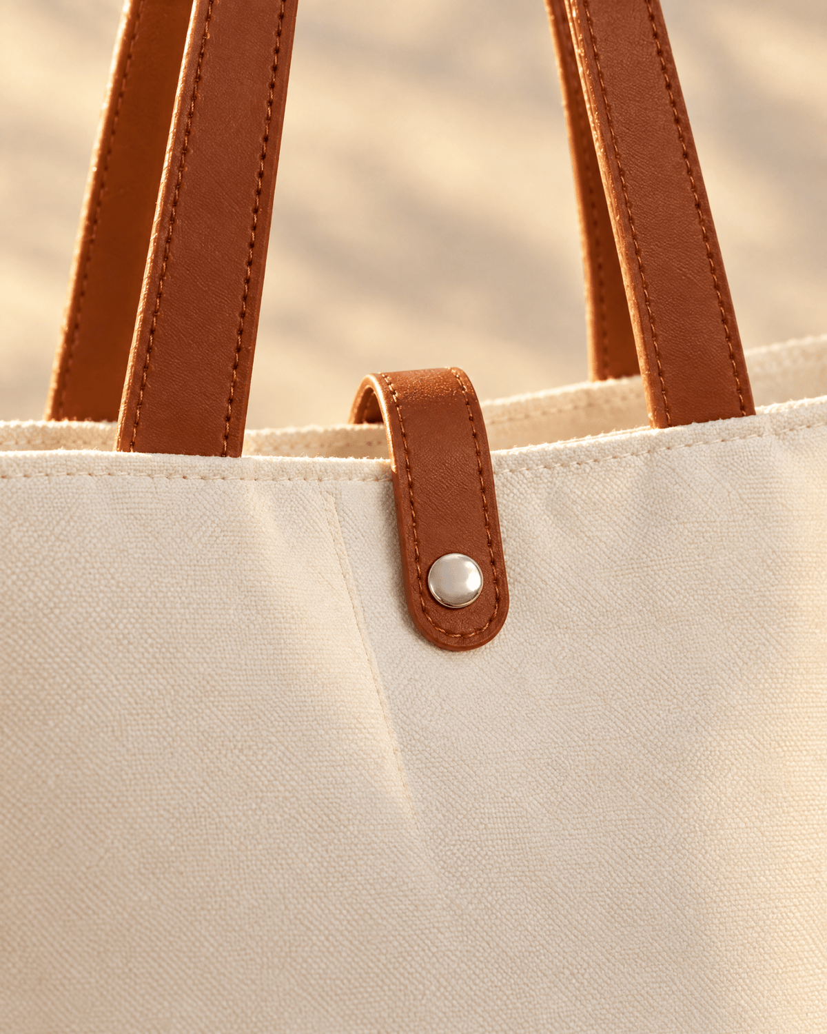 Close-up of the Caleta Tote's brown snap tab and stitched leather-look handles