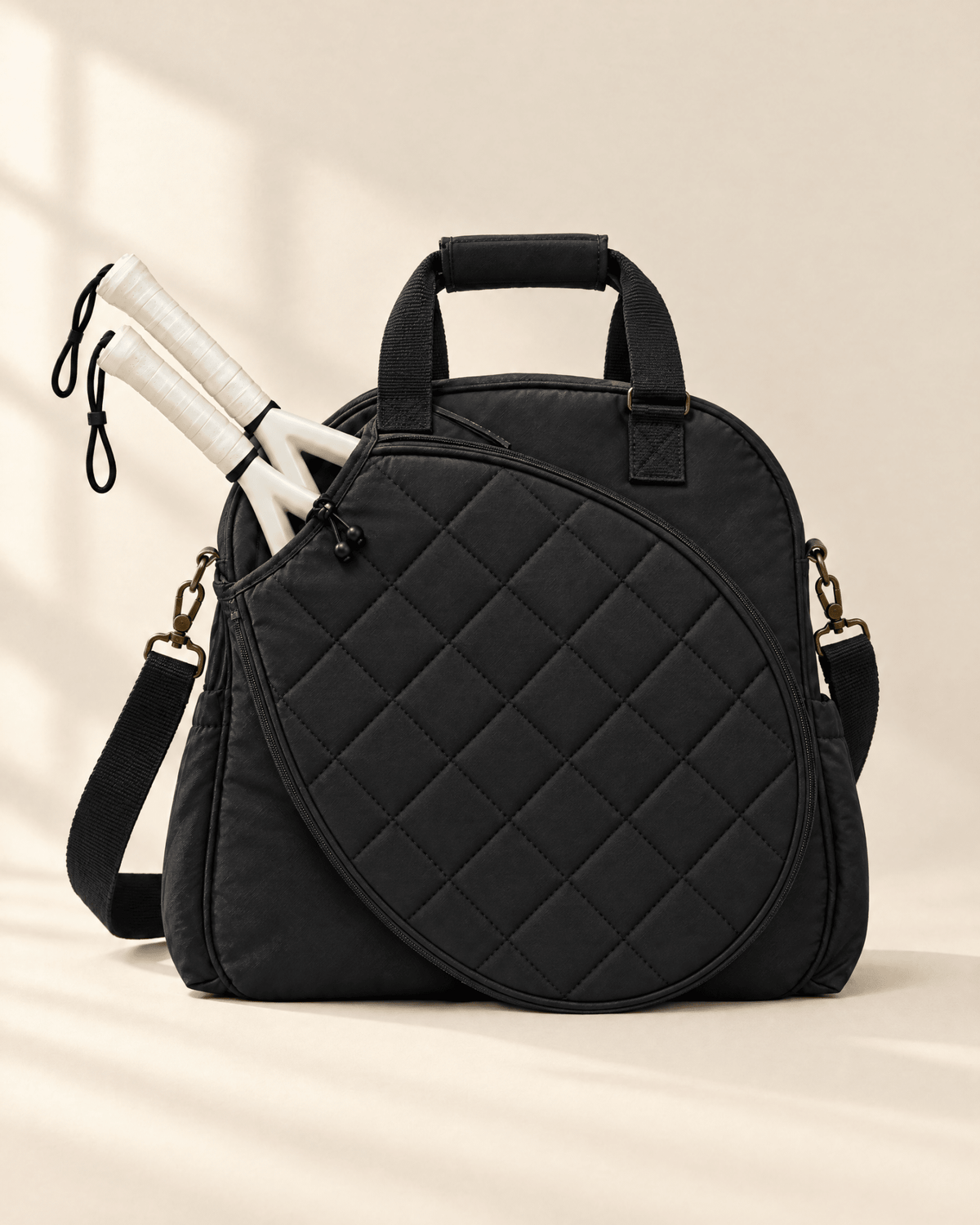 The Las Brisas Racket Bag in black, with two padel rackets in the quilted front compartment