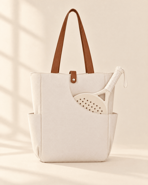 The Caleta Tote in white with brown handles, a padel racket in its curved front pocket