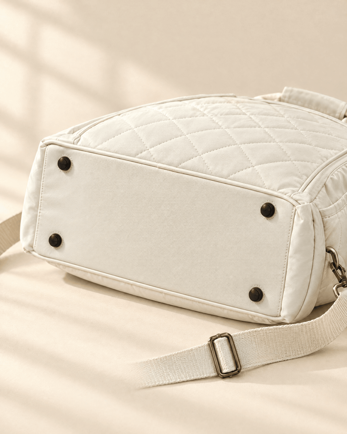 The base of the white Las Brisas Racket Bag with four protective feet, and the shoulder strap slider